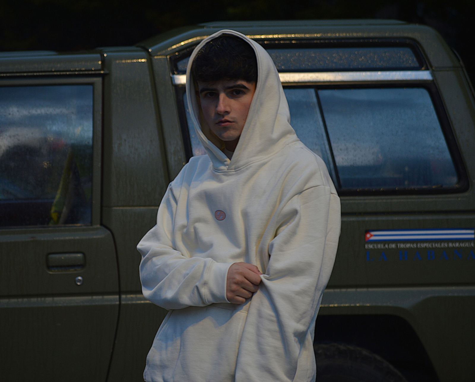 Modelo con la sudadera Horses color crema y la capucha puesta junto a un todoterreno